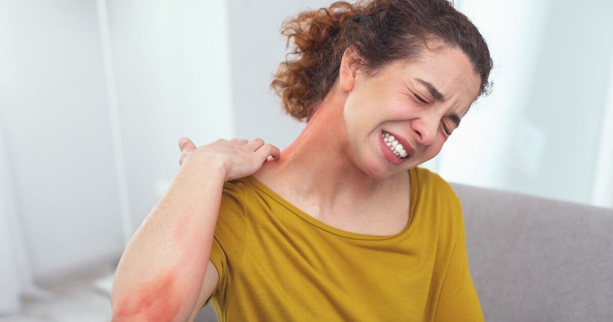 Woman grimacing in pain while rubbing her neck and shoulder