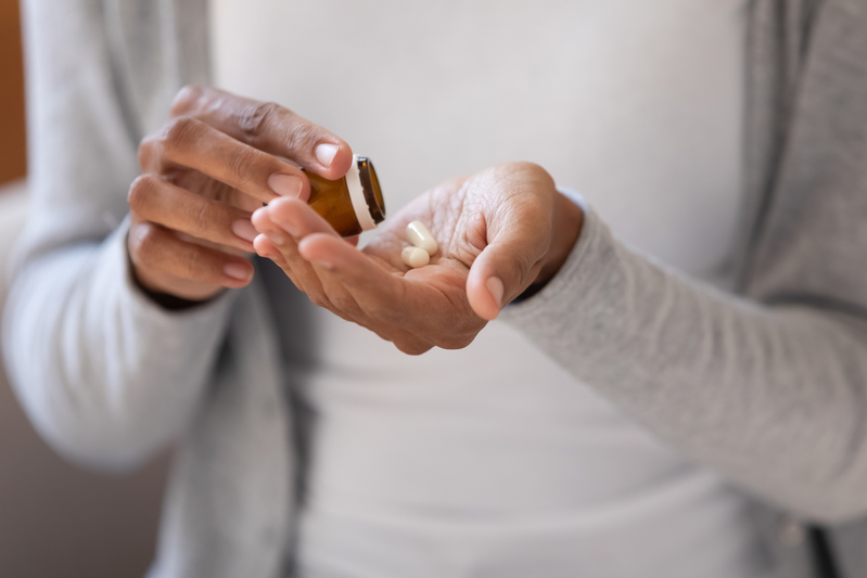 person shaking out pills from bottle into their palm